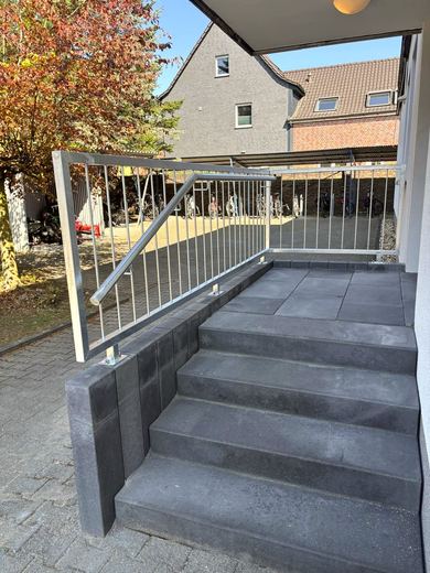 Stabgeländer an einer Eingangstreppe aus dunklen Blockstufen
